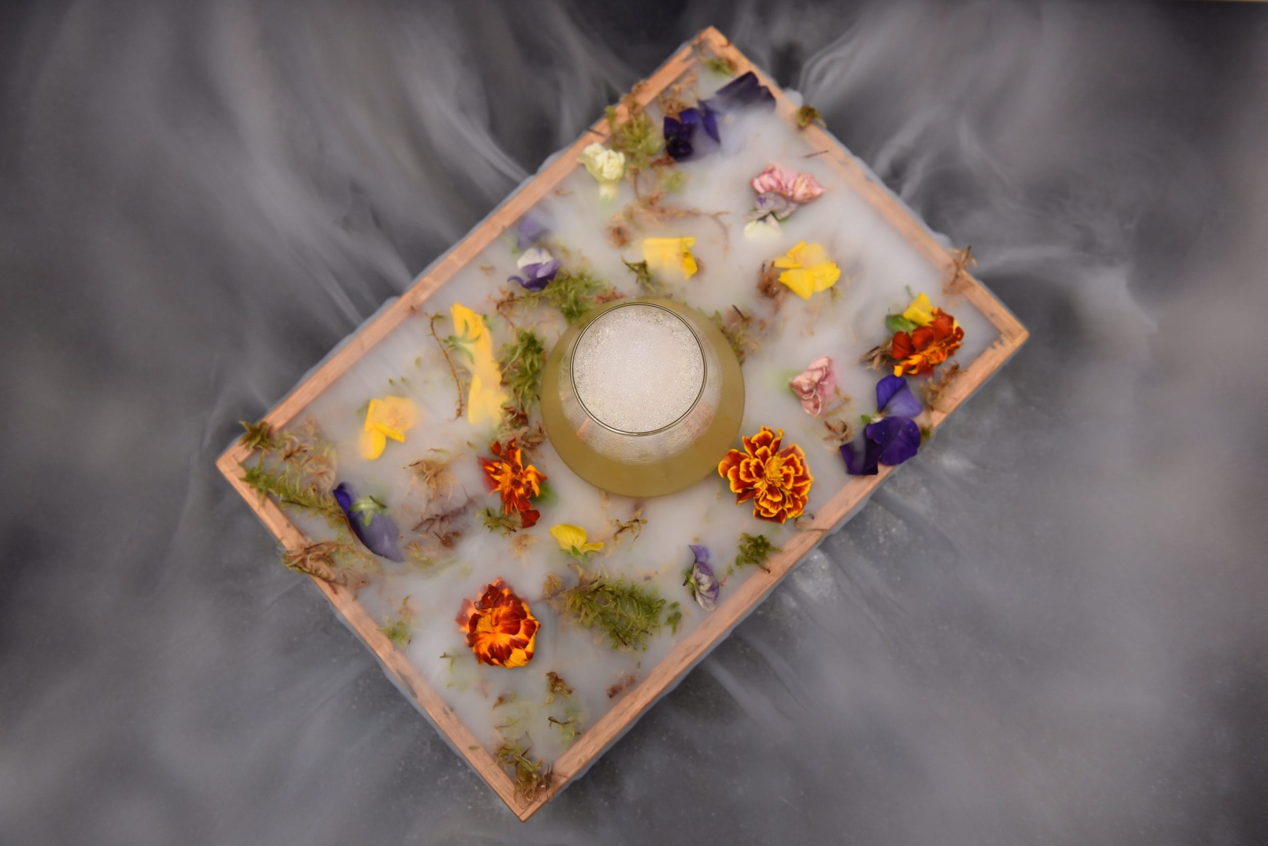 molecular cocktail served on a tray with fog and flowers during a luxury cocktail bar hire package