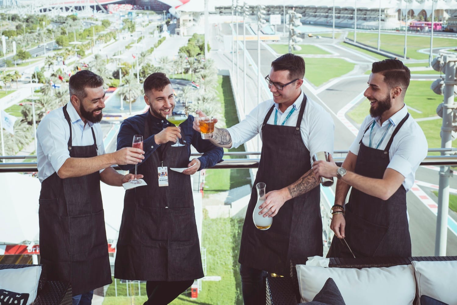 Four Mr Flavour mixologists on a Yas Marina suite terrace overlooking the circuit at the Abu Dhabi Grand Prix
