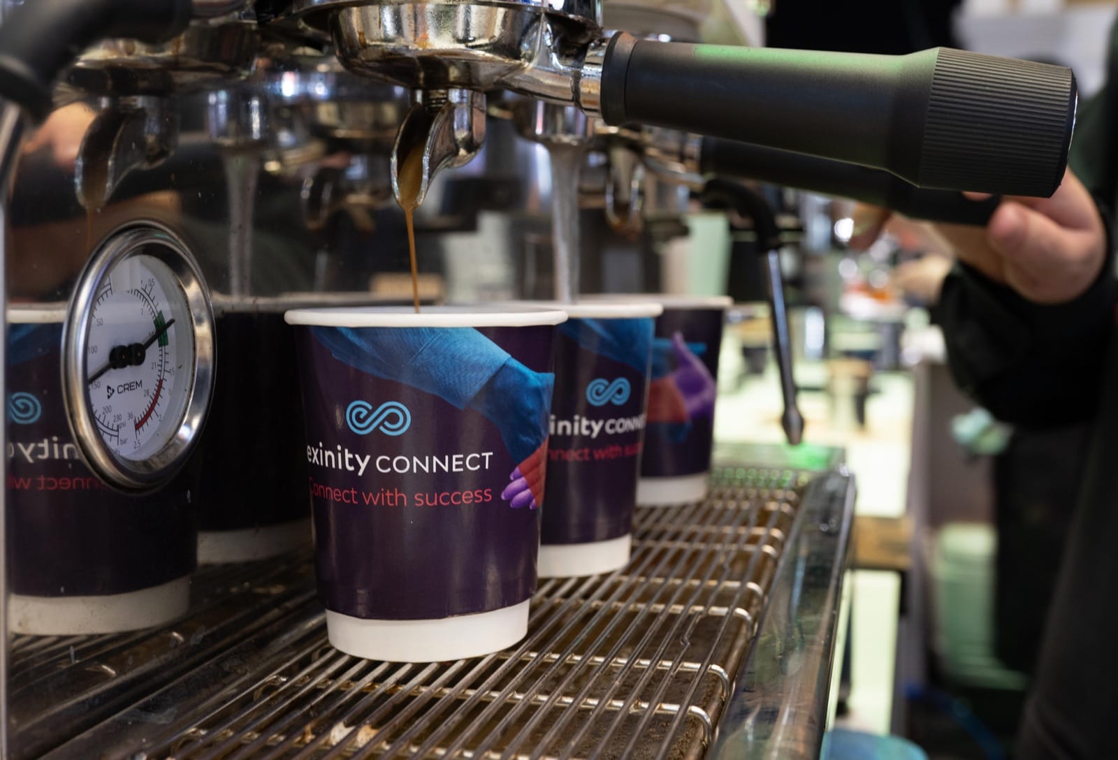 Branded Exinity Connect coffee cups filled at a Mr Flavour barista station at the Finance Magnates London Summit