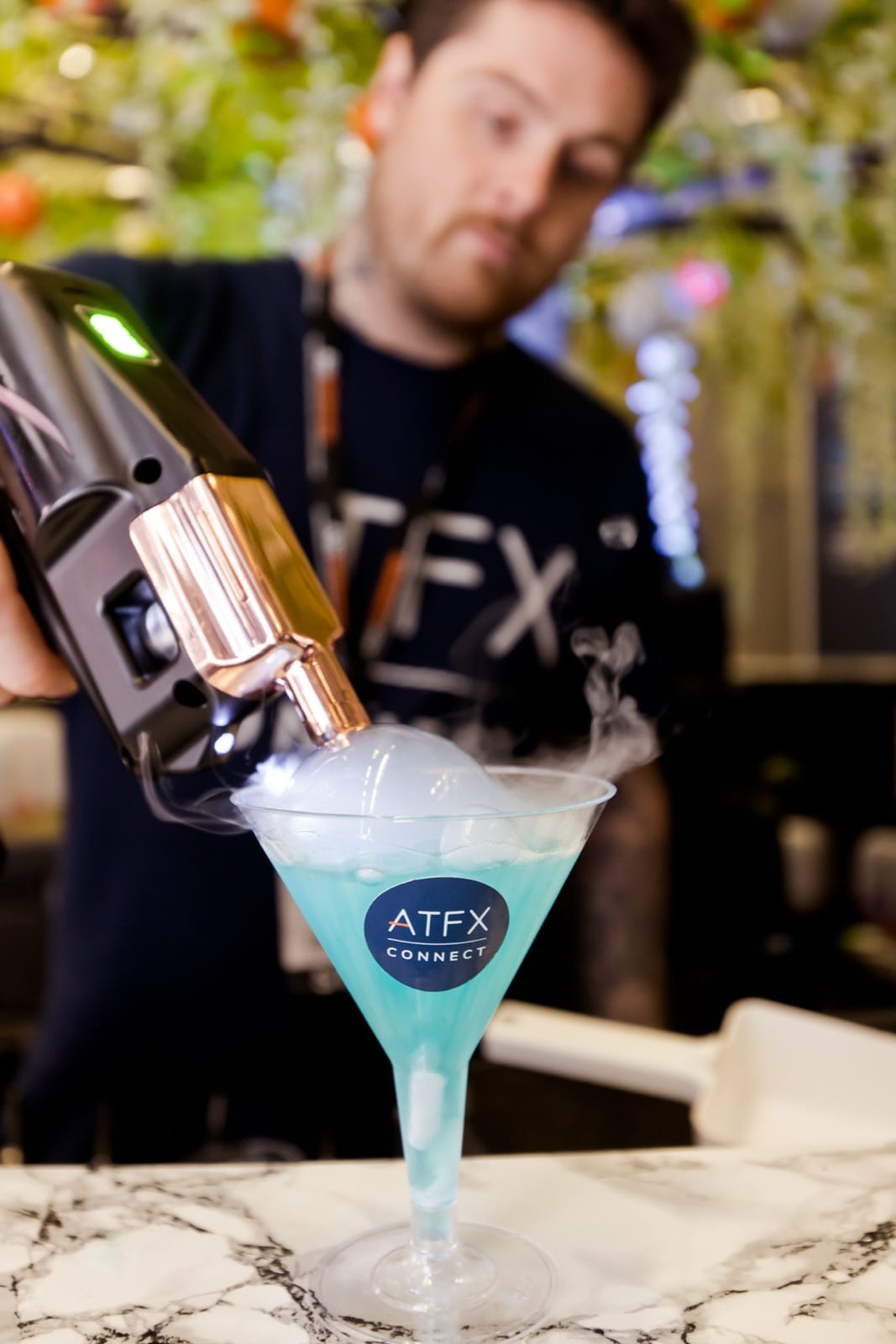 A Mr Flavour mixologist torch-finishing an ATFX-branded dry ice cocktail at the Finance Magnates London Summit