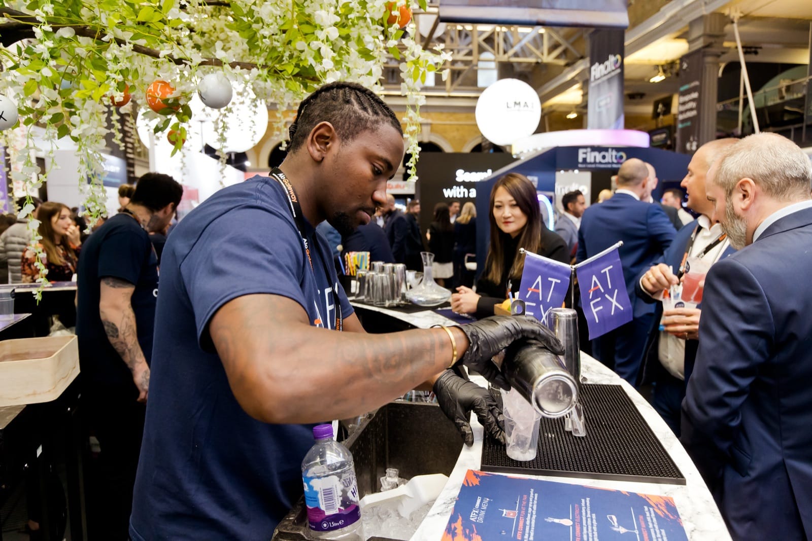 A Mr Flavour bartender serving branded drinks to delegates at an exhibition stand bar at the Finance Magnates London Summit
