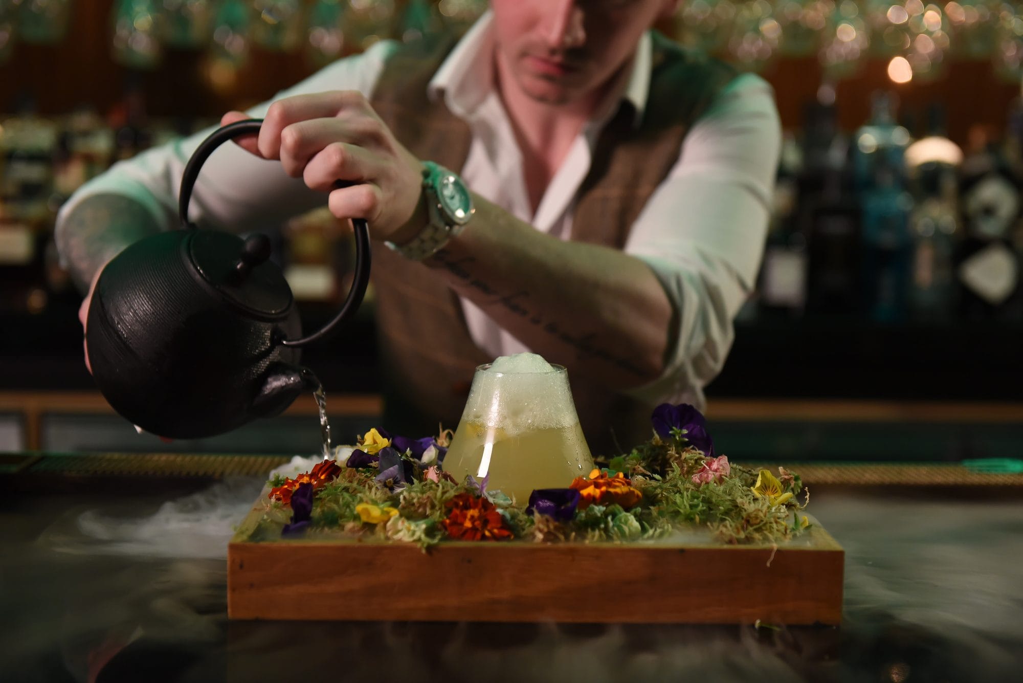Mr Flavour bartender pouring an English Garden cocktail over a floral presentation board