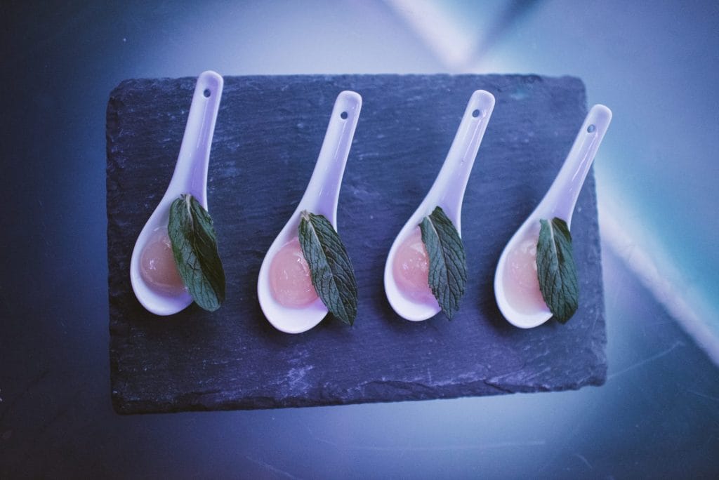 Mojito spheres presented on ceramic spoons across a slate board