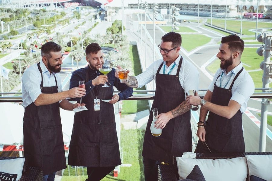 Four of the Mr Flavour team in aprons on a trackside balcony at an international race weekend