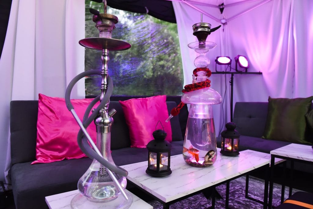 Styled shisha lounge with draped cabana, lounge seating and illuminated glass shisha pipes at a Mr Flavour event
